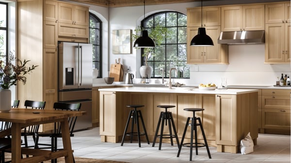 A large bright kitchen with VEDHAMN oak fronts and a kitchen island with two pendant lamps above it and bar stools in front.