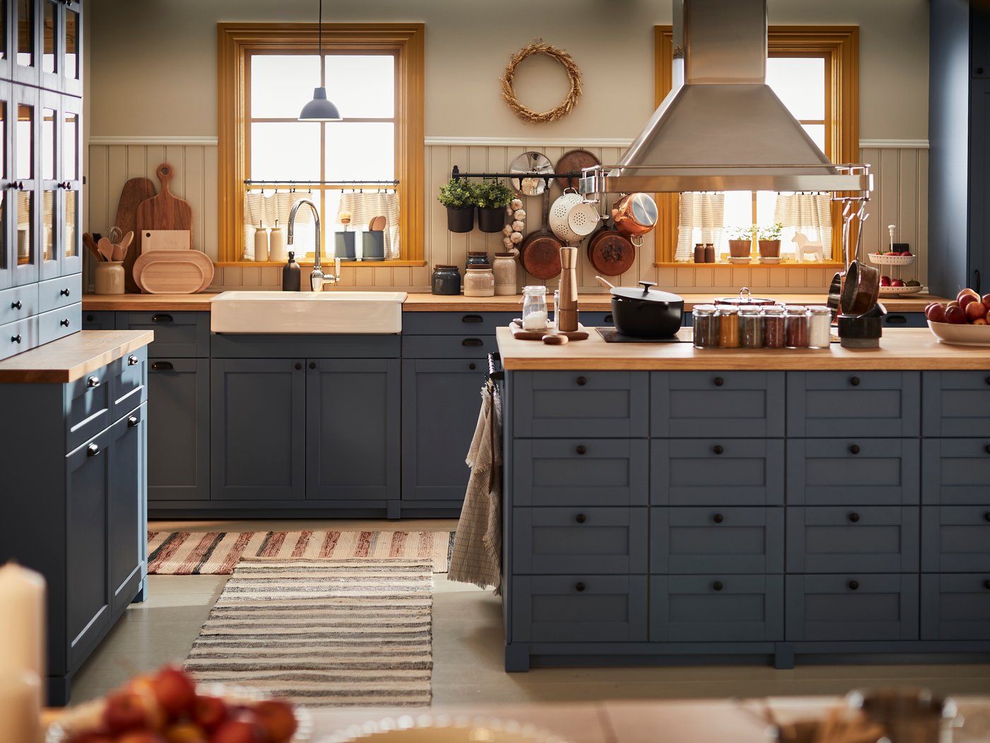 Eine dunkelblaue Küche mit einer Kücheninsel in der Mitte und Arbeitsplatten aus Holz.