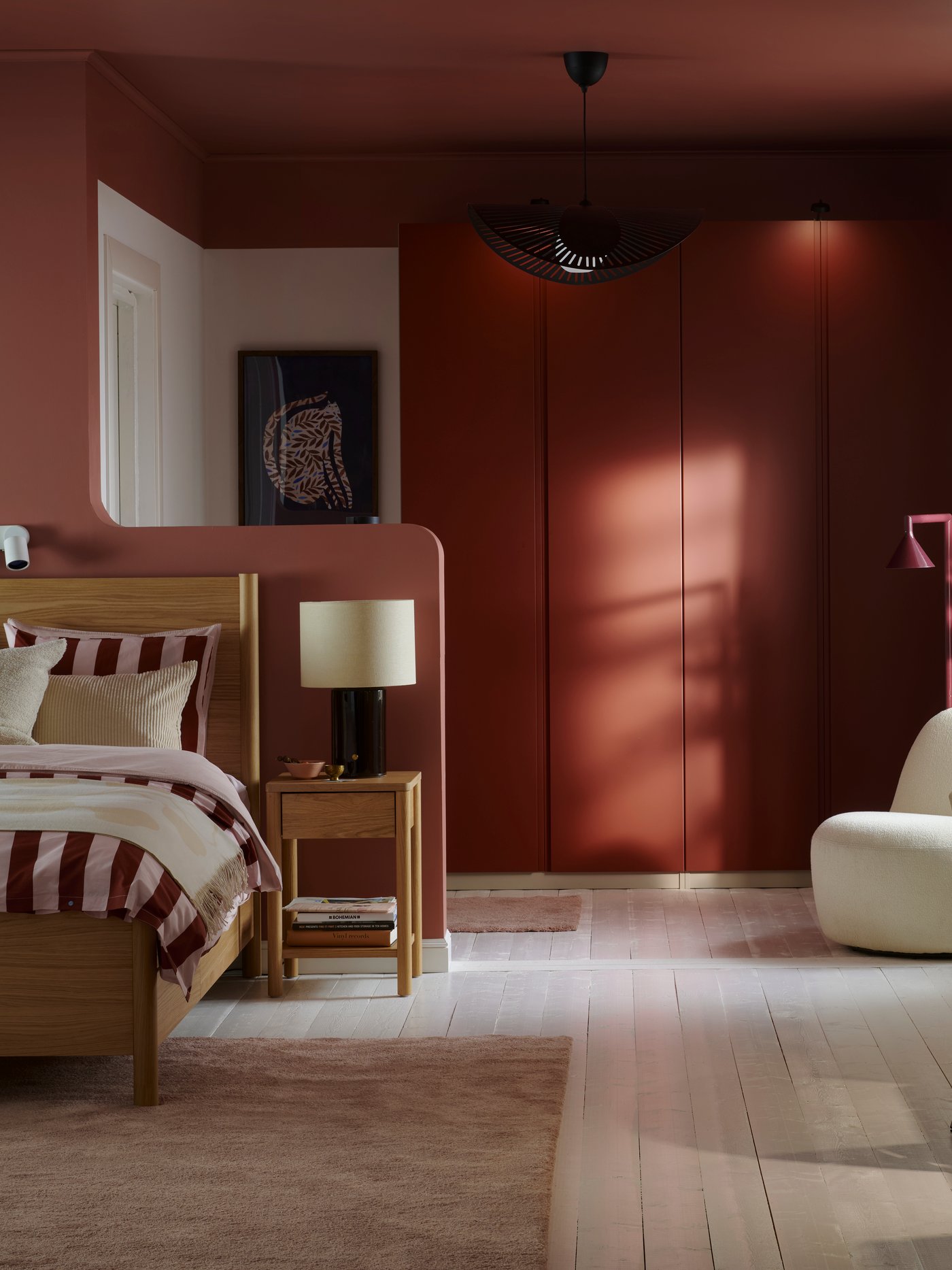 A bedroom with white floors and an oak veneer TONSTAD bed with striped bedding and PAX wardrobe with orange VIKANES doors.