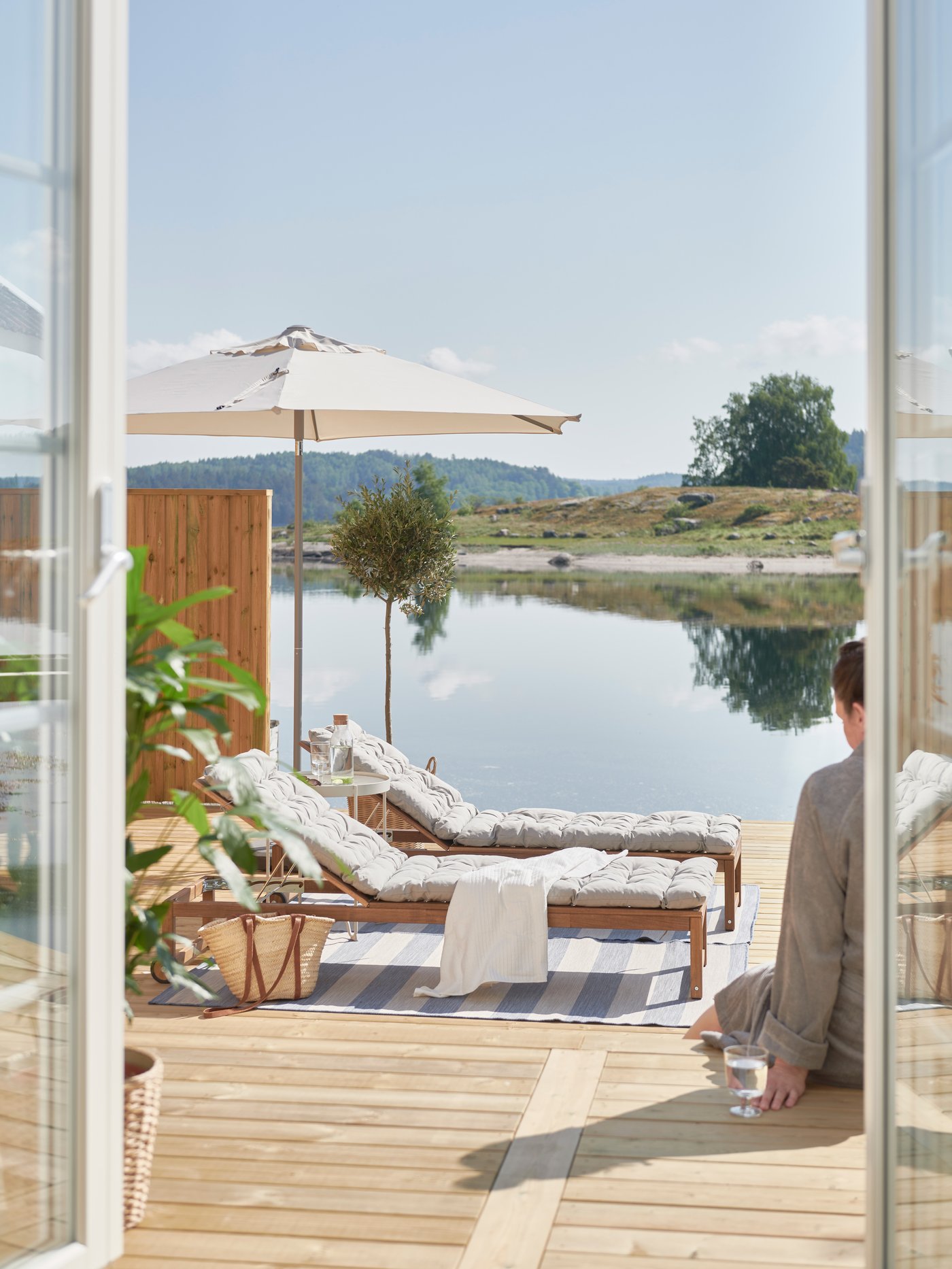 Brygga med två NÄMMARÖ solsängar och en sjö i bakgrunden.