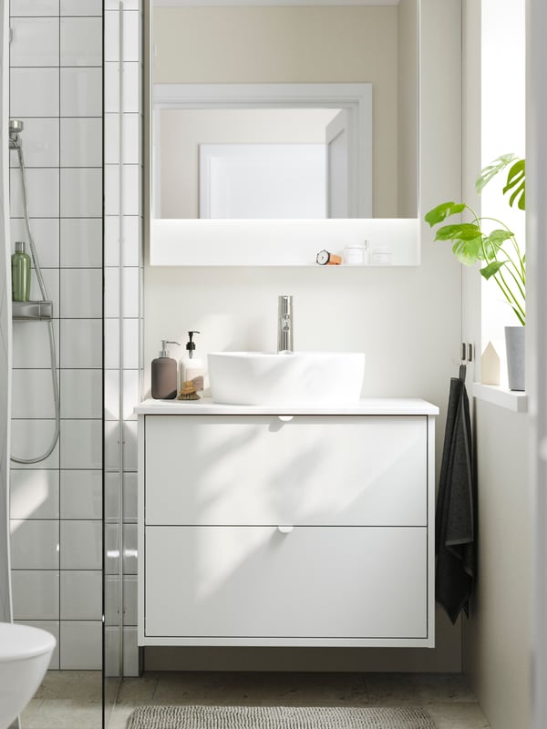 A bright bathroom has a shower, a HAVBÄCK wash-stand with drawers, a TÖRNVIKEN countertop wash-basin and a FAXÄLVEN mirror.