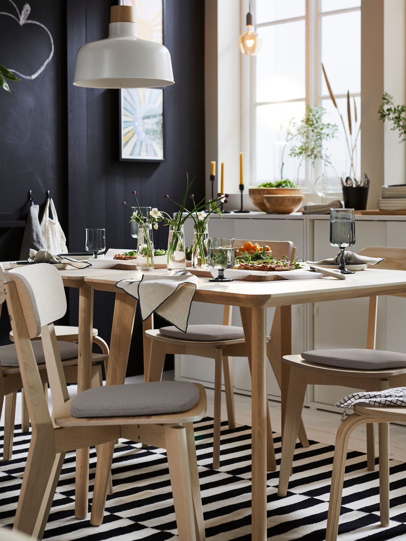 Два стола LISABO из ясеневого шпона и несколько стульев LISABO из ясеня стоят на ковре STOCKHOLM черного и бежевого цветов.