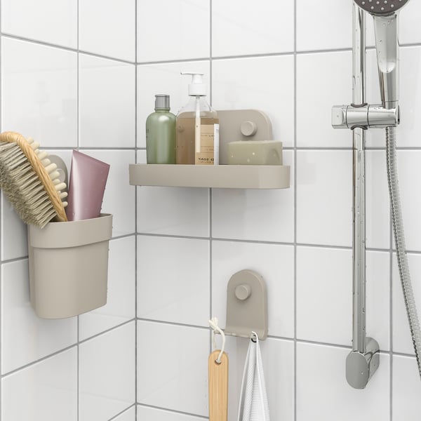 Shower wall with tiled background, holding shelves and hooks with bottles, brush and accessories