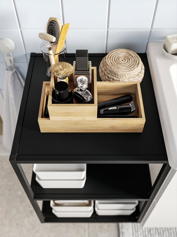 An ENHET base frame with shelves in anthracite seen from above with some TAVELÅN trays and other objects on it.