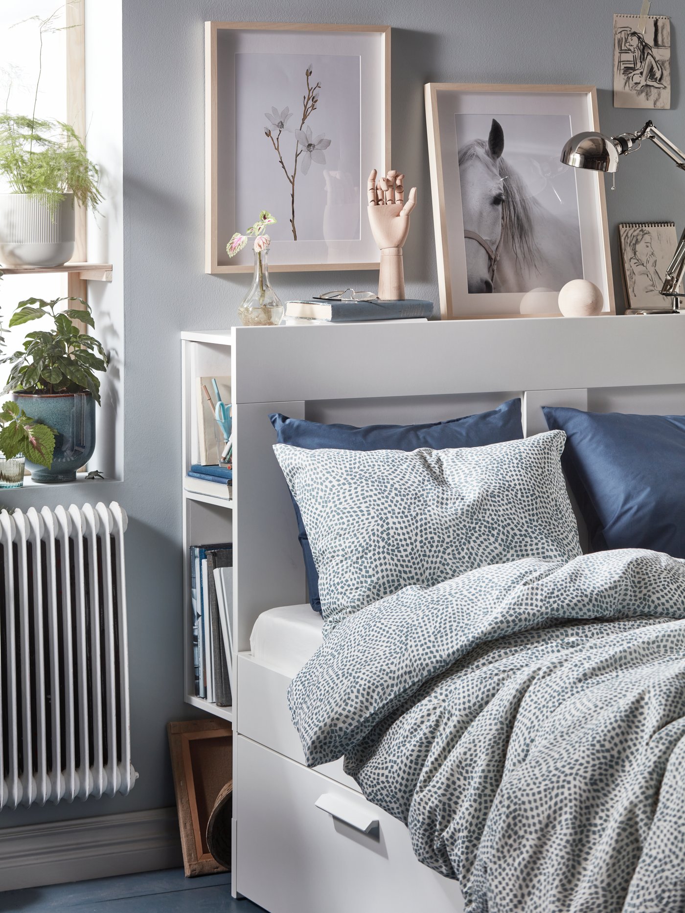 A bright bedroom in gray tones with a white BRIMNES bed frame and storage space behind the headboard.