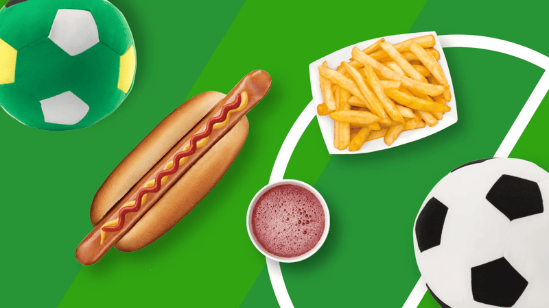 na boisku zielonym leżą piłki do gry i hot dog
