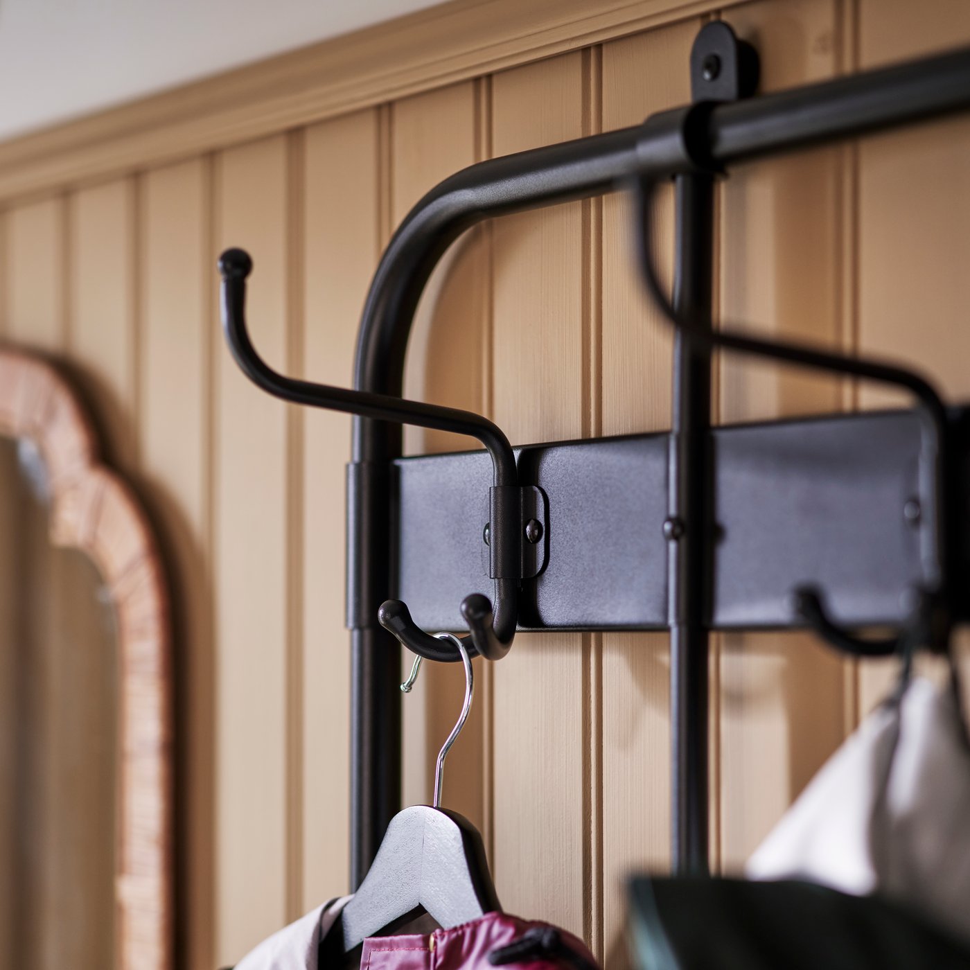 A close-up of the top corner of a NIPÅSEN coat rack and bench with shoe storage shows two hooks, one holding a coat hanger.