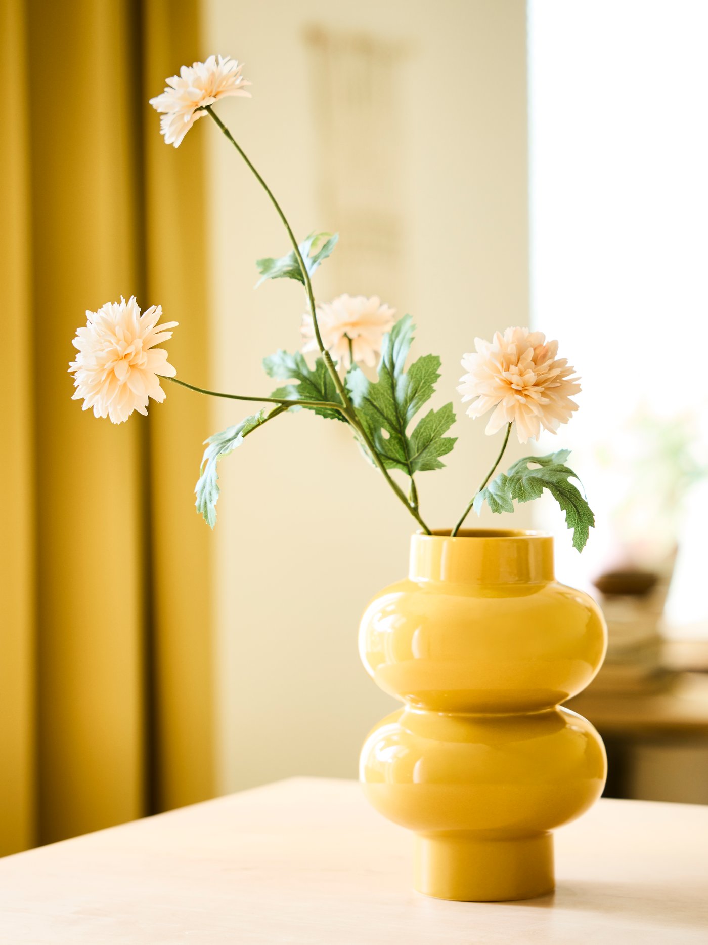 A yellow KÄLLARHALS vase with a SMYCKA artificial chrysanthemum flowers.  