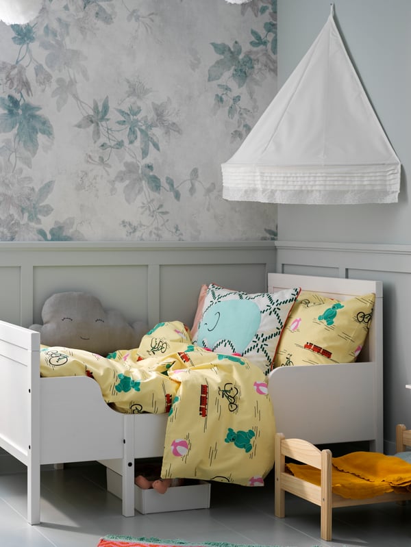 A white SUNDVIK bed covered with a cushion and yellow KÄPPHÄST bed linen and with a white LEN bed canopy above it.