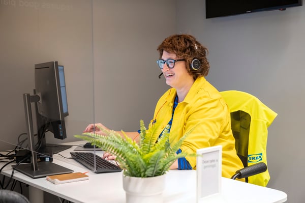 Une collaboratrice du service clientèle IKEA est assise devant un écran et discute avec un client