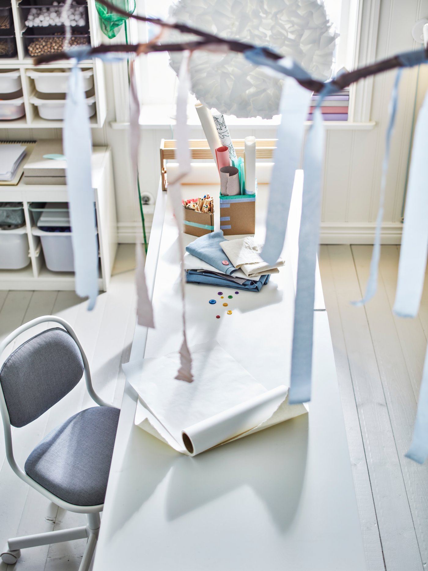 Habitación para bebés y niños con un escritorio rectangular de madera, una silla de escritorio infantil, varias cajas de almacenaje y un marco.