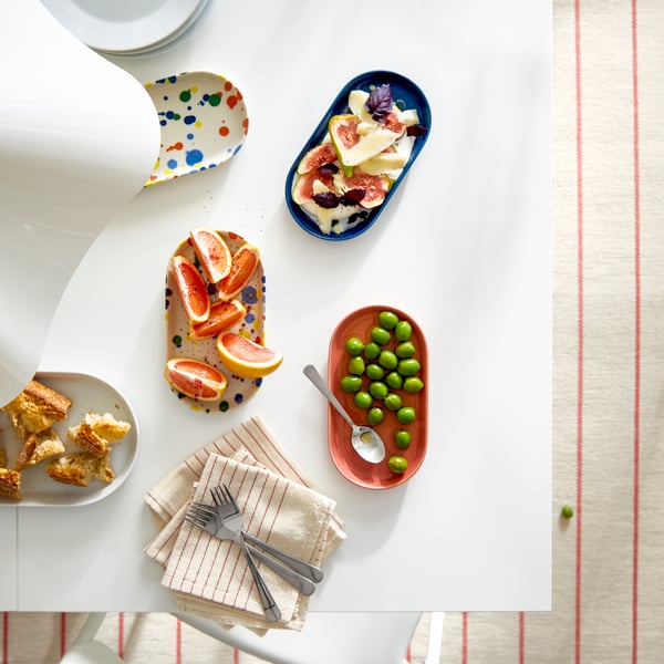 A styled table displaying an array of colourful dishes with fresh fruits, including a blue serving platter.