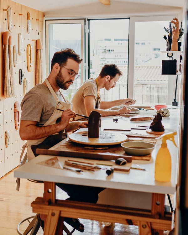 Beide Männer arbeiten konzentriert an ihrem Tisch. 