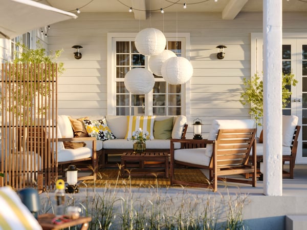 An outdoor space with a NÄMMARÖ 4-seat conversation set, some cushions and several SOLVINDEN LED solar-powered pendant lamps.