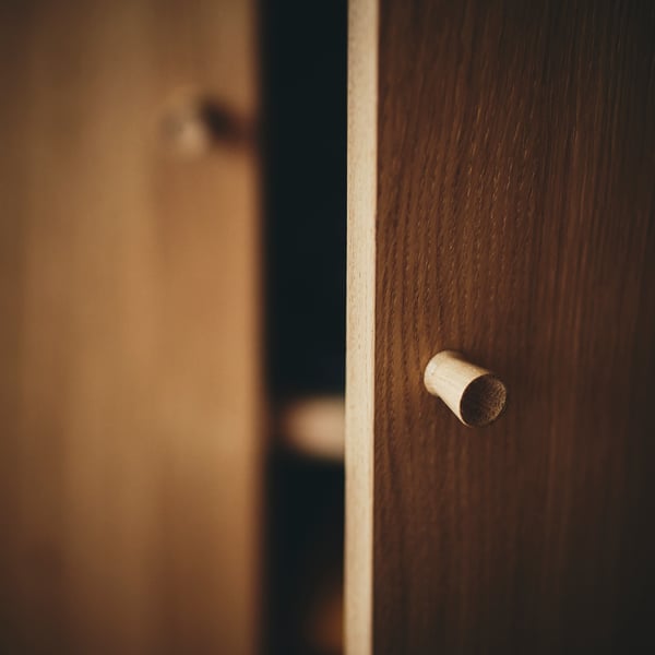 An oak veneer TONSTAD cabinet with doors with one door slightly open showing part of a shelf inside.