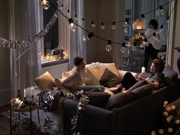 Drei Personen feiern eine Silvesterparty mit festlicher Deko zuhause.