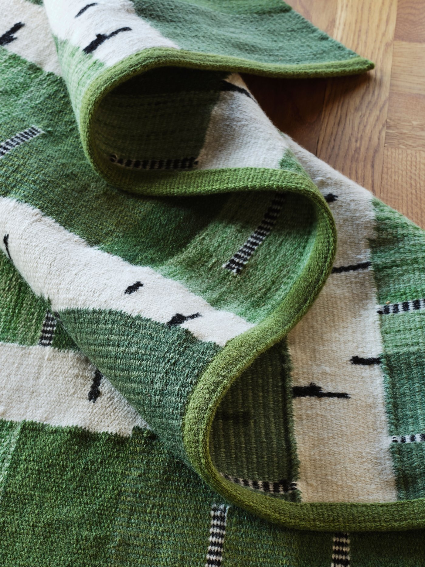 A green/white/black handwoven STOCKHOLM 2025 rug, flatwoven