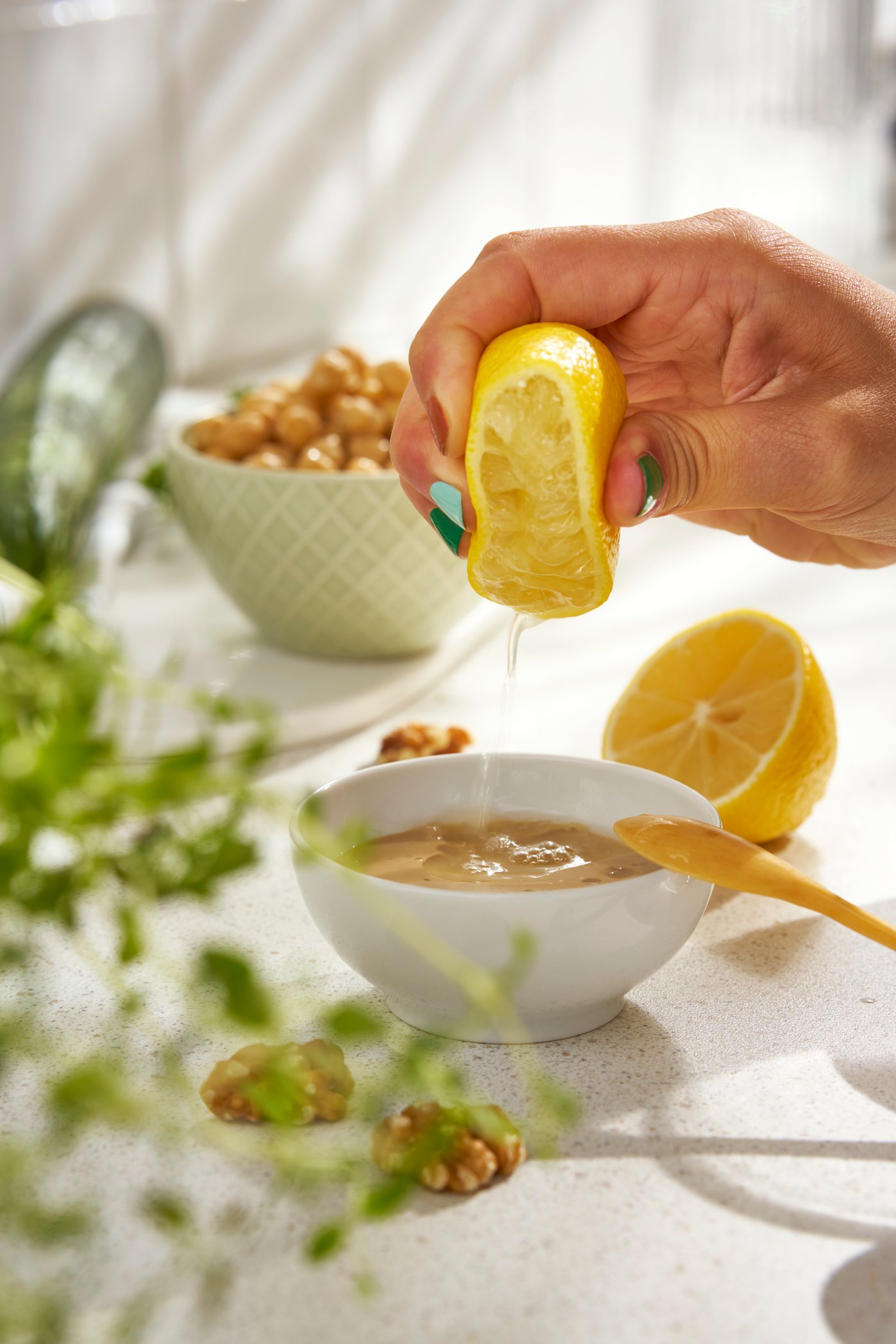 Ruka cedi limun u KEJSERLIG činiju s umakom. U pozadini se vidi još jedna KEJSERLIG činija s leblebijama.