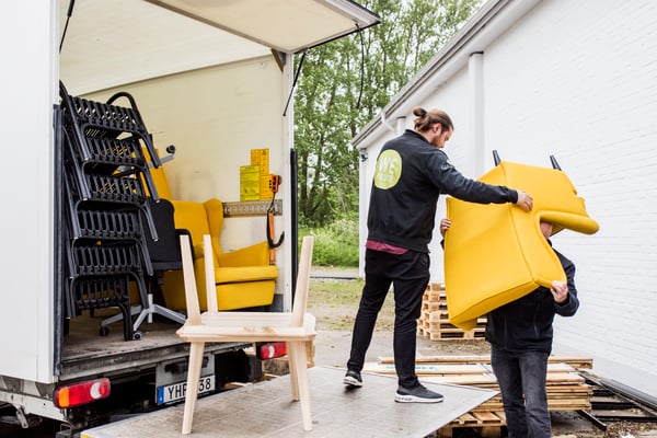 IKEA removal service: Two people lifting a yellow armchair into the back of a van.