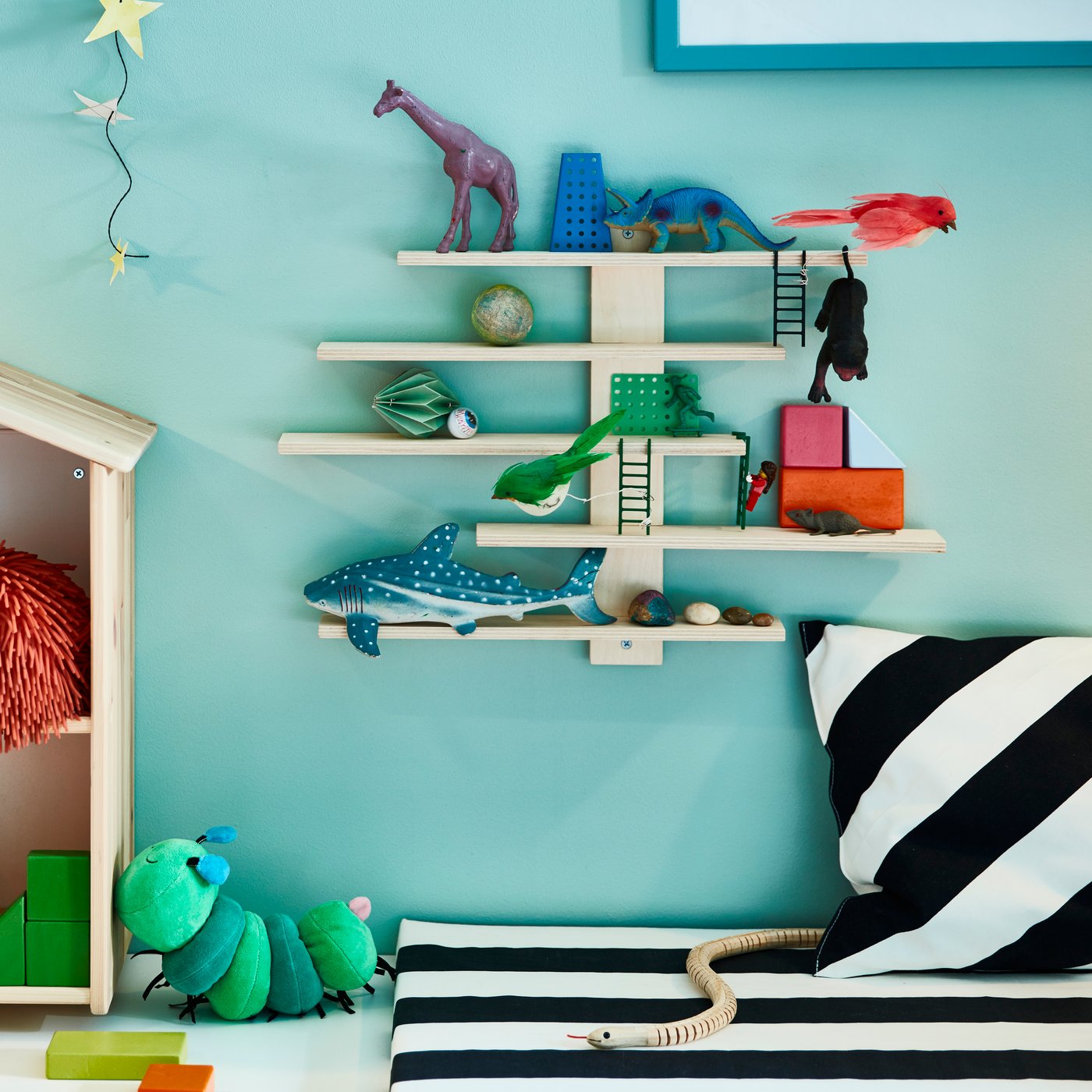 Una repisa de madera LUSTIGT en la pared de un dormitorio infantil con juguetes de dinosaurio.