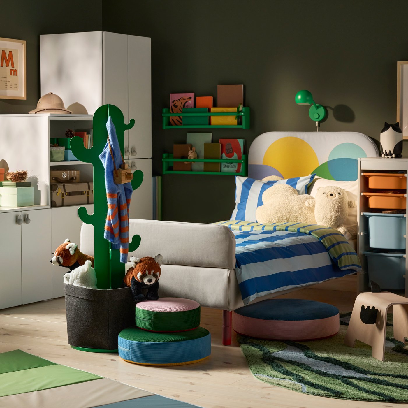 A child’s bedroom with a GRYSNA bed in multicolour fabric, green cactus clothes stand, wild animals and green wall shelves.