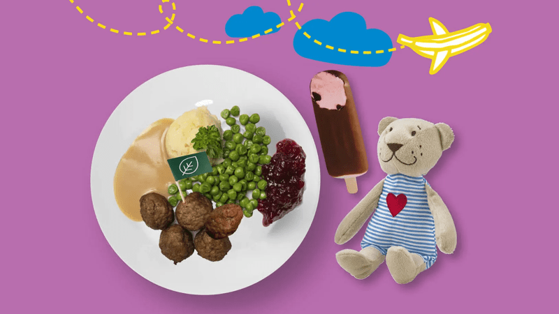 Kuvassa FABLER BJÖRN -pehmolelu, joka tulee lastenaterian mukana. Ateriaan kuuluu pyörykät, muusi, herneet ja hillo sekä jäätelöpuikko! Kuvan yläosassa lentää lentokone.