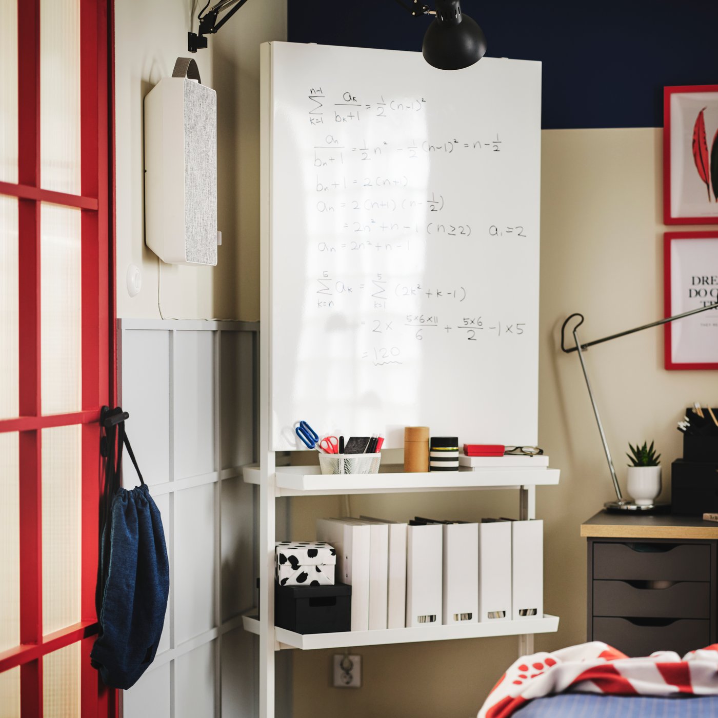 A MITTZON frame with castors, whiteboard and shelf in a corner of a room with a FÖRNUFTING air purifer on the wall beside it.