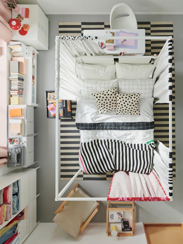 A bird’s-eye view of a bedroom with a VITARNA four-poster bed in the middle covered in black and white VIKTLÖVER bed linen.