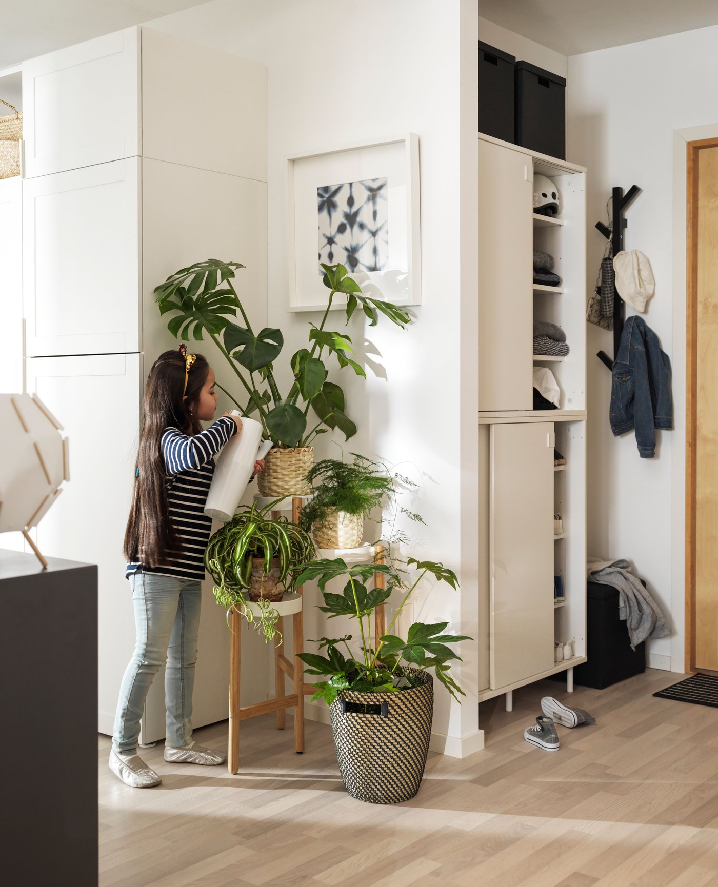 Dziewczynka podlewająca rośliny na stojaku SATSUMAS.