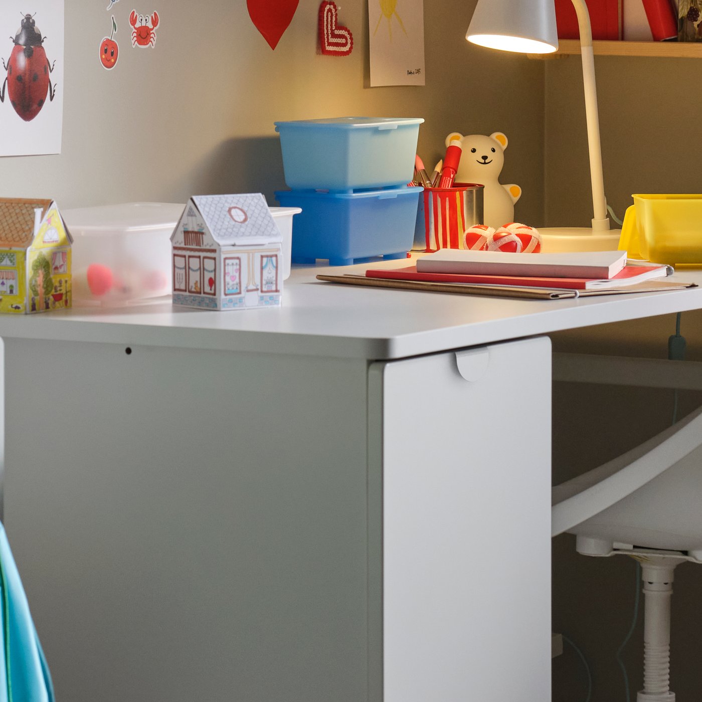 A white LÄRANDE desk with a pull-out storage unit, a white children’s desk chair and a pine/white wall storage combination.