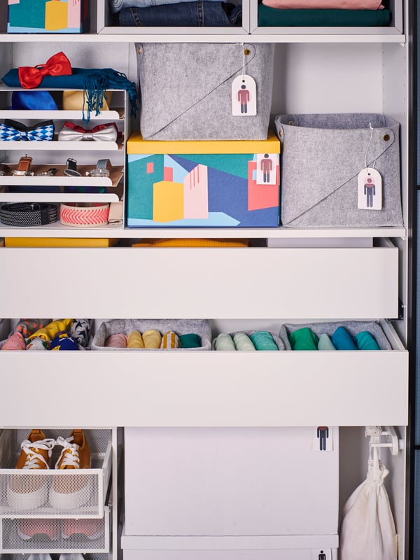 Gros blanc sur des tiroirs d'un dressing. Une boîte de rangement TJENA jaune avec couvercle dans la chambre