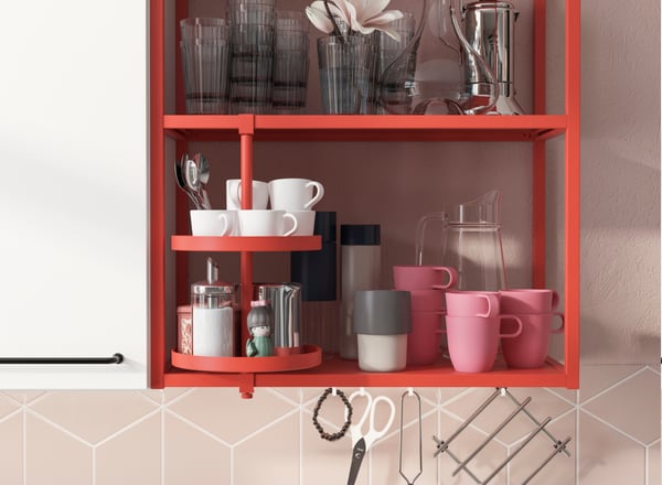 Gabinete color rojo con contenedores y menaje de cocina en su interior, color blanco, gris, rosado y transparente. 