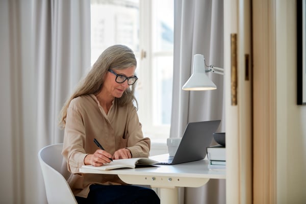 Une femme planifie son espace en utilisant son ordinateur portable, posé devant elle. 