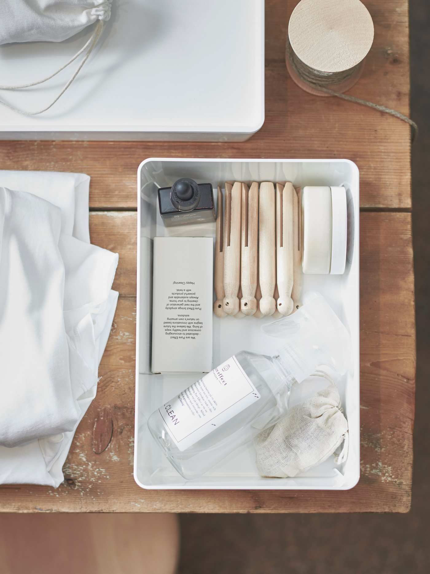 A wooden storage box with a handle and three levels holding scissors, string, paint and a stapler on the top level.