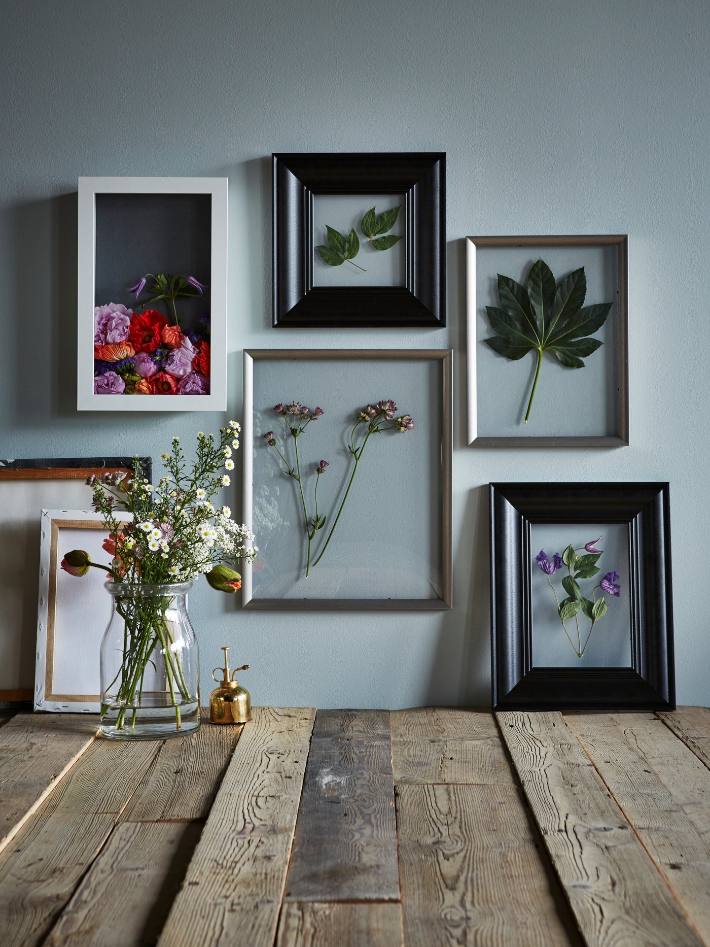 verschiedene Bilderrahmen an einer hellblauen Wand  - stehend und hängend.