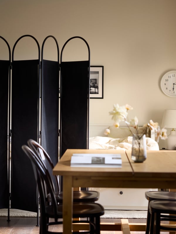 GRÅFJÄLLET room divider in Anthracite separates the space between the guest bed and the kitchen table.
