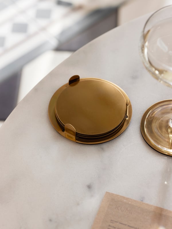 Gouden onderzetters GLATTIS op een tafel