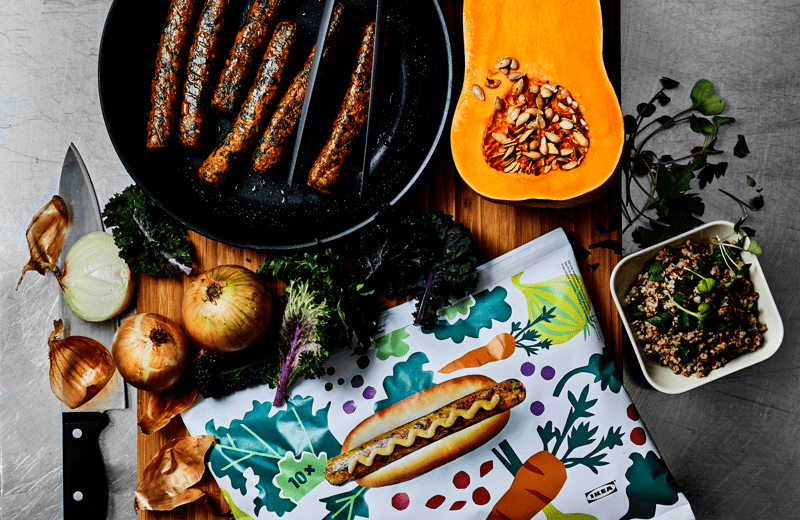Un hot-dog, des légumes et un couteau sur une planche à découper.