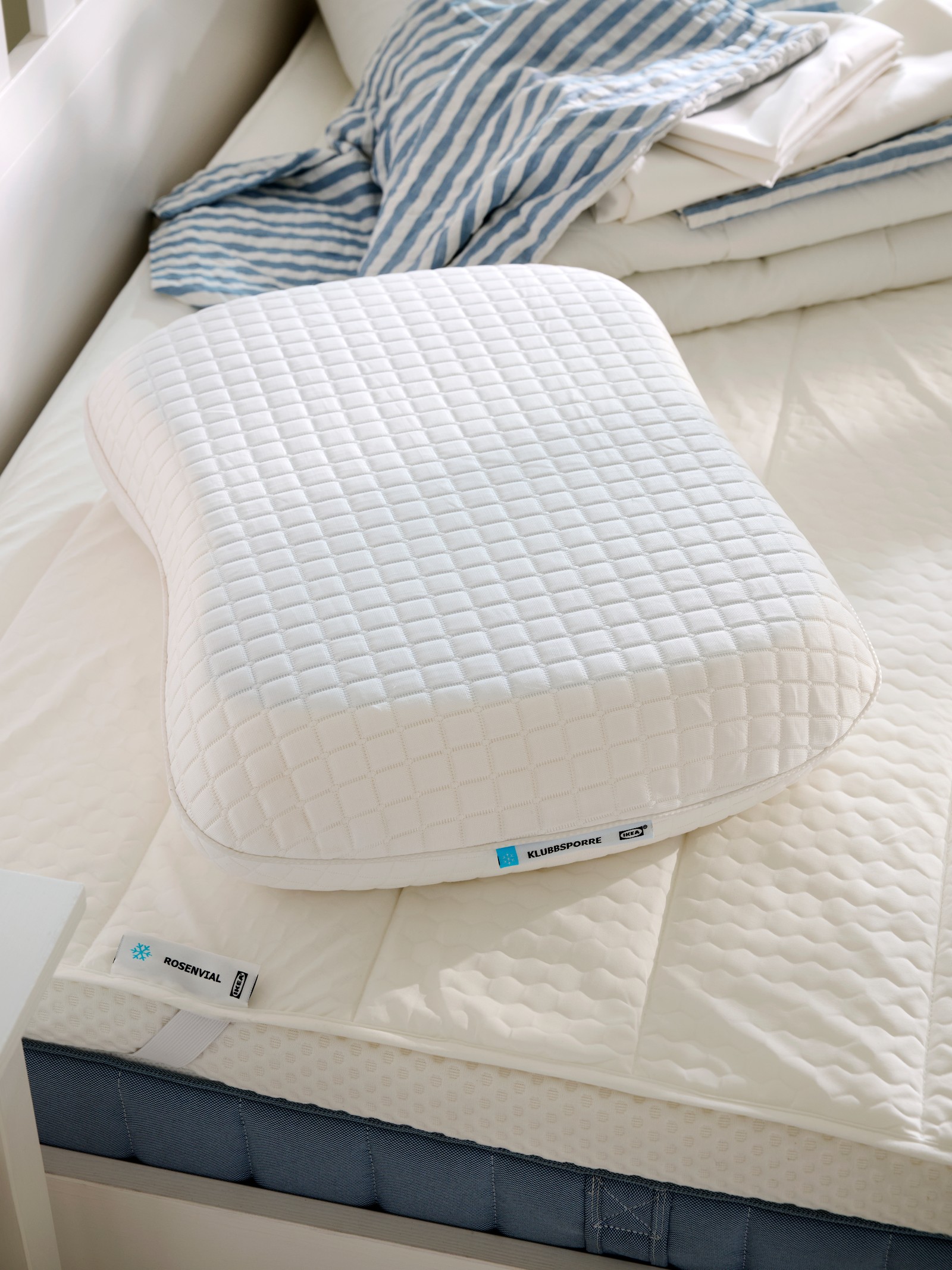 Close-up of KLUBBSPORRE ergonomic pillow on top of ROSENVIAL mattress protector, both with a cooling effect.