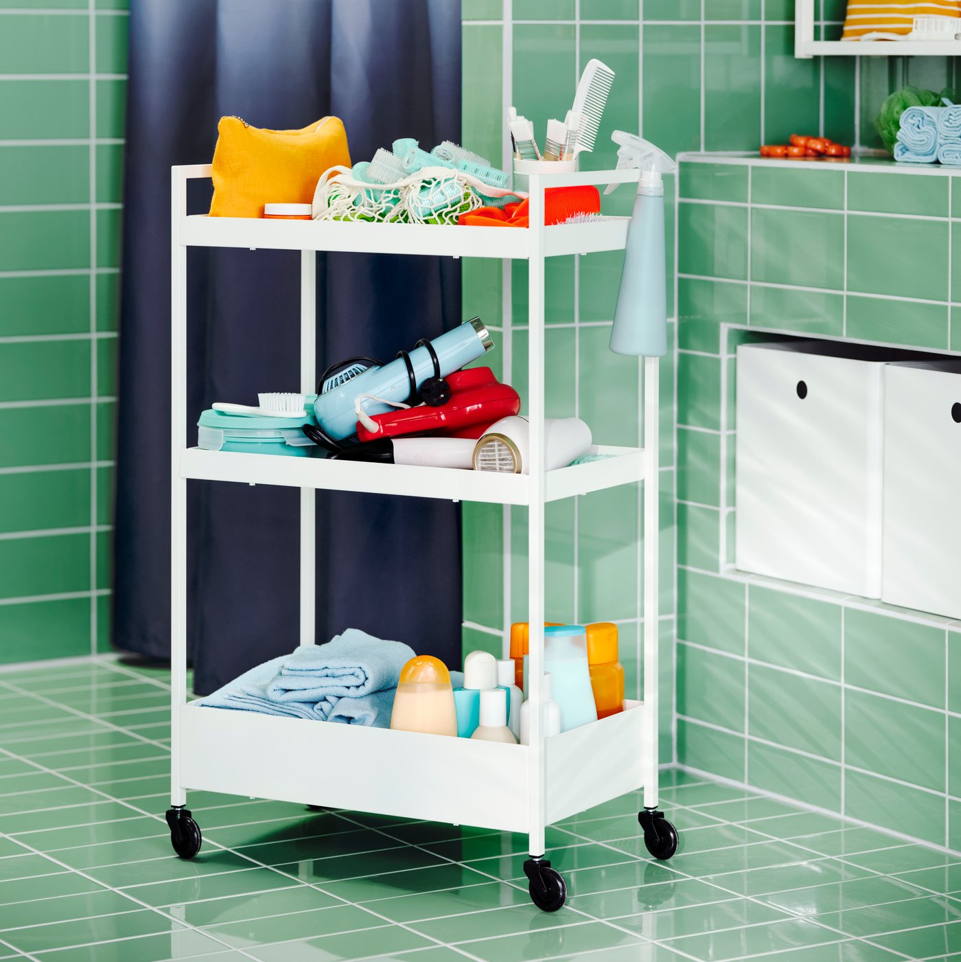 Carrito NISSAFORS color blanco con accesorios de baño, dentro de un baño con paredes de color turquesa.