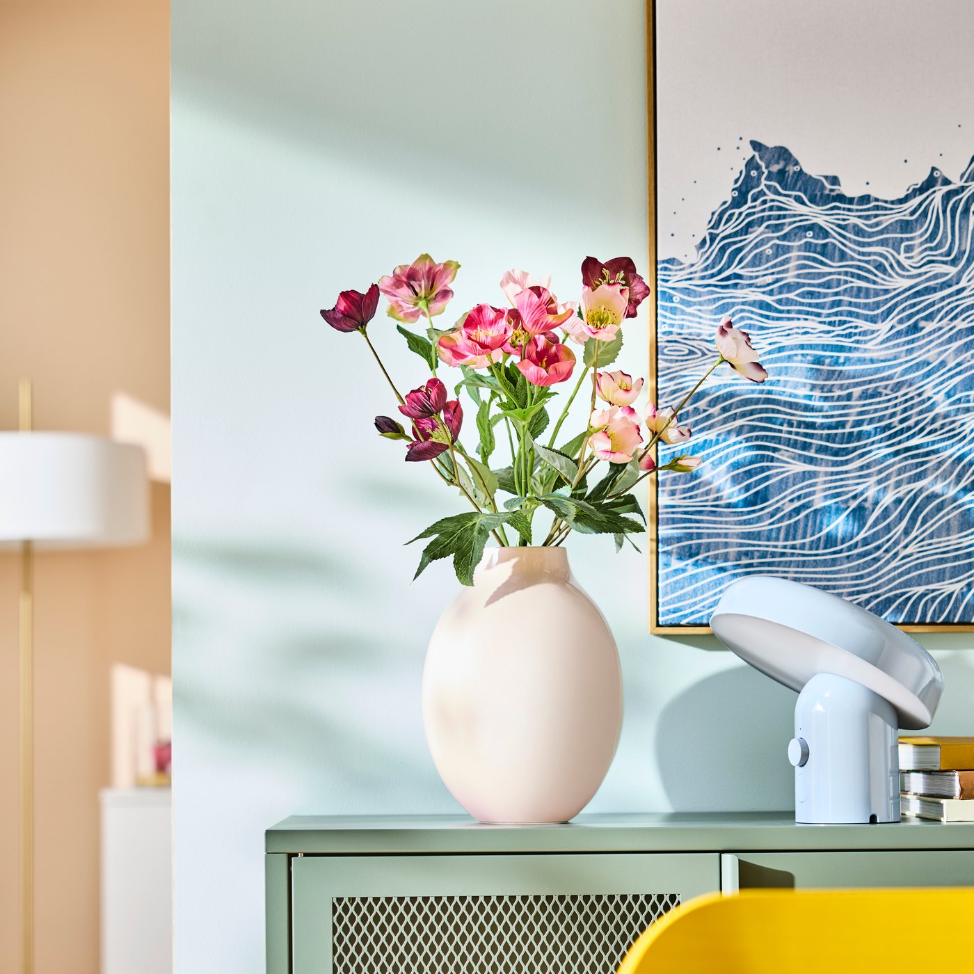 Eine BLODBJÖRK-Vase in Beige mit buntem Blumenstrauß auf einem grünen Sideboard
