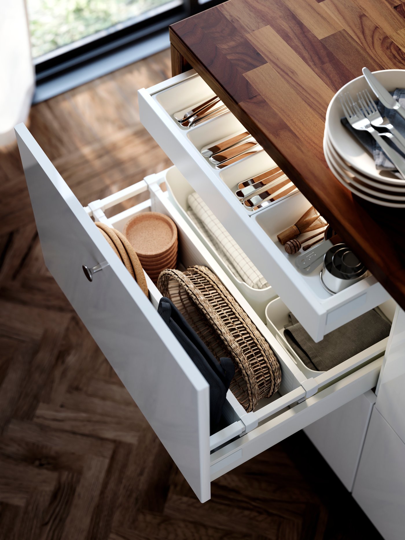 A large drawer in a cupboard with white RINGHULT kitchen doors is pulled out and contains neatly organised kitchen utensils.