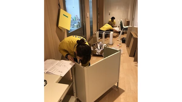 廊下で家具を組み立てる人物