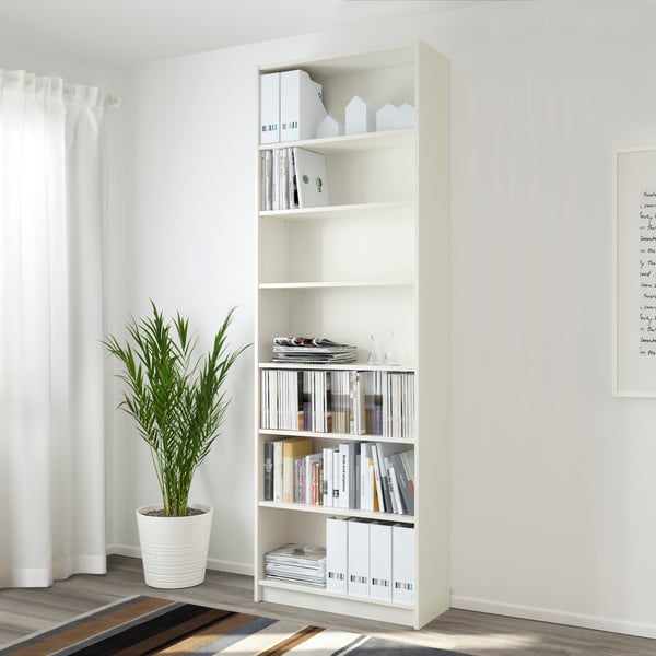 Ein weißes BILLY Bücherregal, 80 breit, 40 tief und 237 hoch, steht vor einer weißen Wand. 