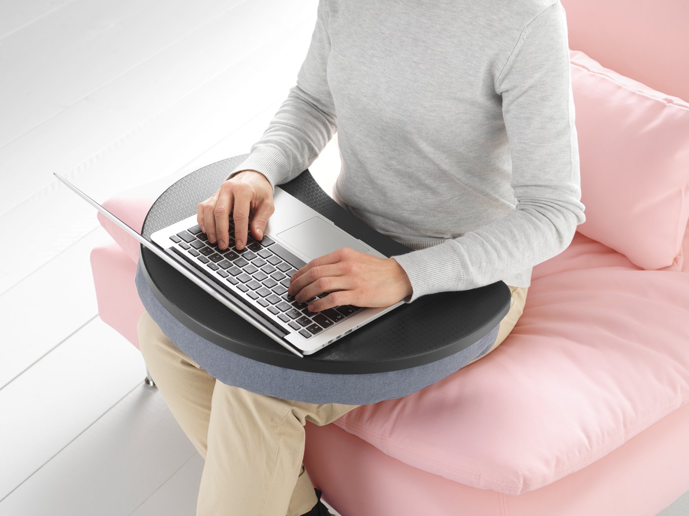 Imagine cu o persoană care ține un laptop în poală și care stă pe un fotoliu roz.