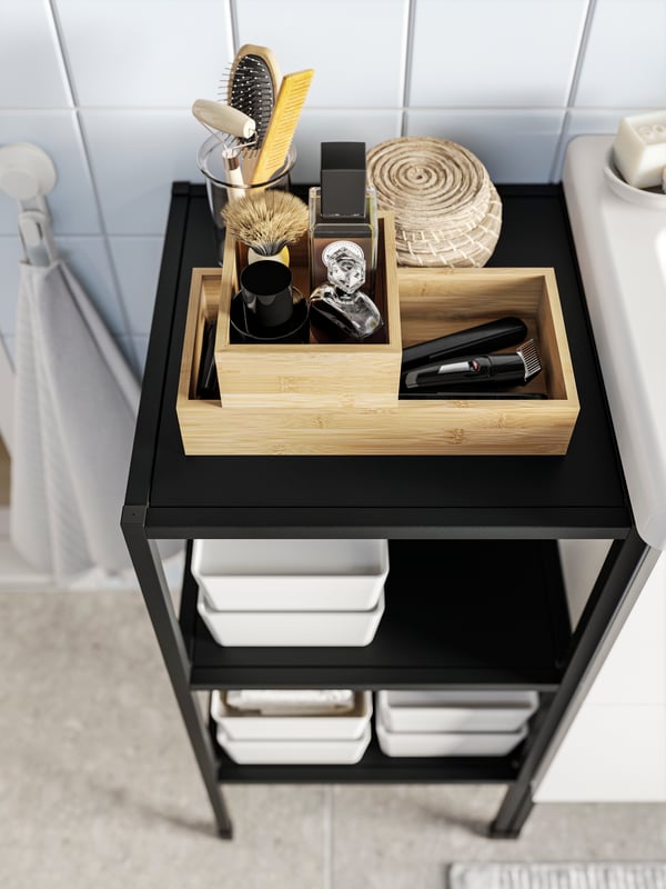 An ENHET base frame with shelves in anthracite seen from above with some TAVELÅN trays and other objects on it.
