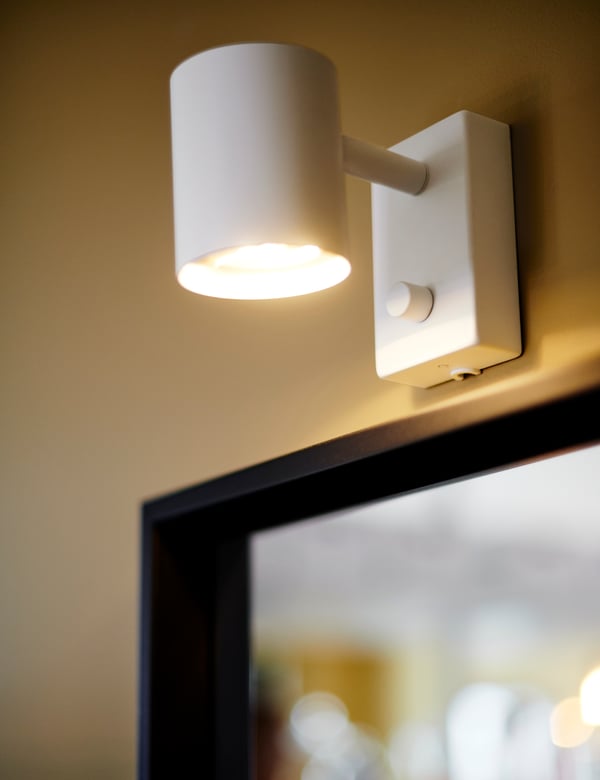 A white NYMÅNE wall/reading lamp, wired-in inst in the living room