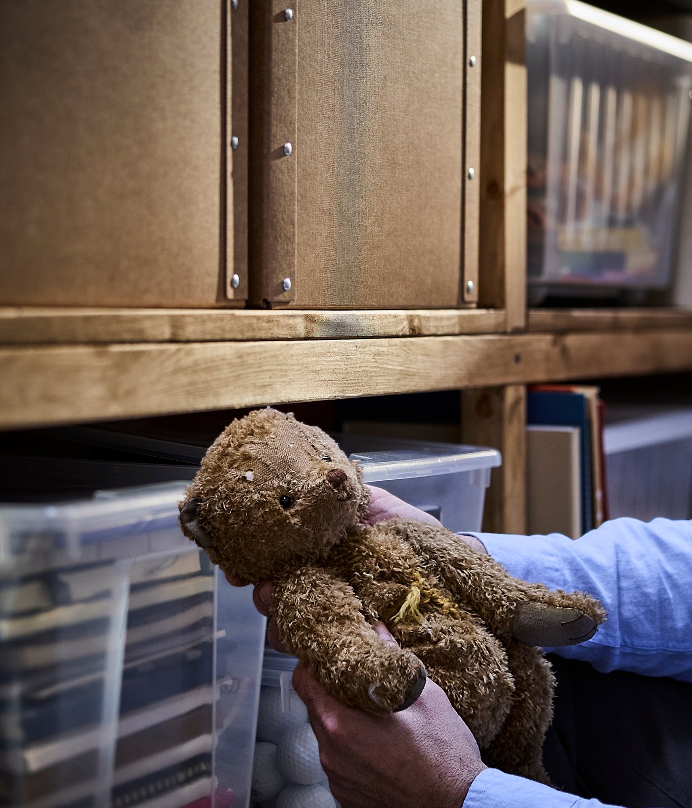 En elsket bamse bliver placeret i en SANLA opbevaringskasse med låg på loftet.