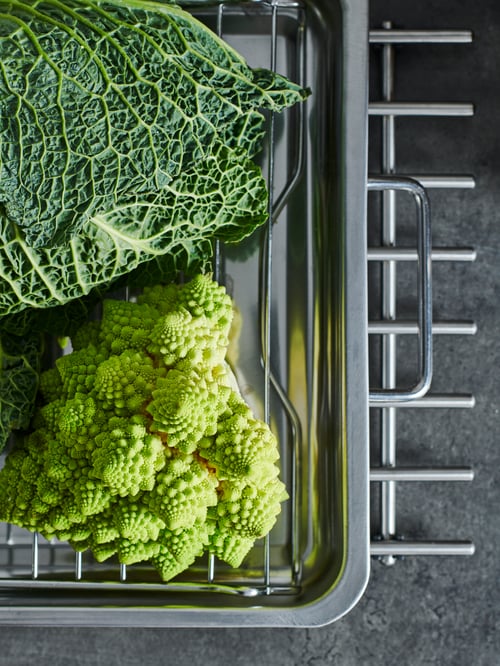 Arbeitsplatte mit Wirsing und Romanesco-Brokkoli in einer KONCIS Ofenform aus Edelstahl, die auf einem LÄMPLIG Topfgitter steht.