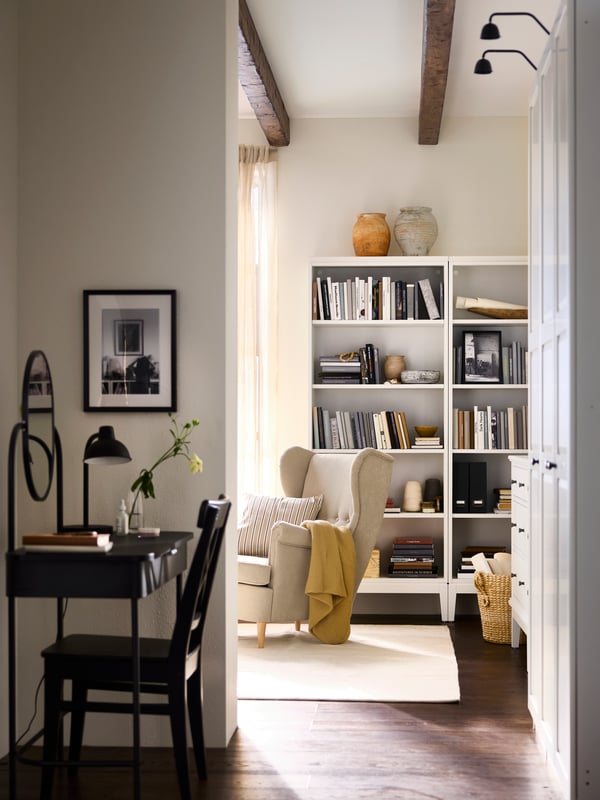 Pathway into bedroom with GRÅFJÄLLET dressing table to the left, wardrobes at right and a bookcase plus armchair further in.